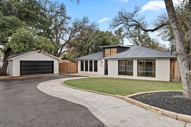 single story home featuring a garage, an outbuilding, and a front lawn