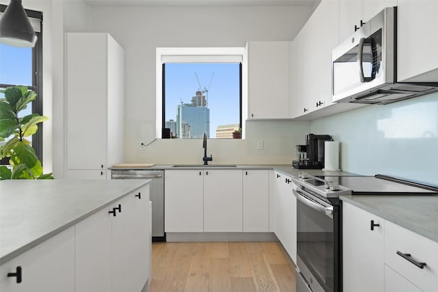 kitchen with sink, white cabinets, decorative light fixtures, and appliances with stainless steel finishes