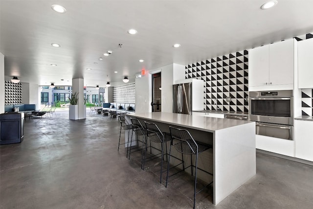 kitchen with a kitchen breakfast bar, stainless steel fridge, a center island, and white cabinets