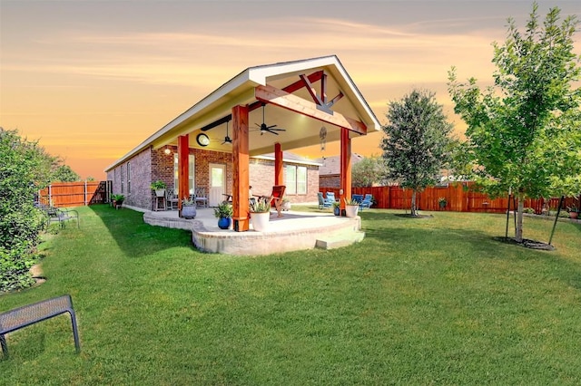 back house at dusk with a patio, a yard, and ceiling fan