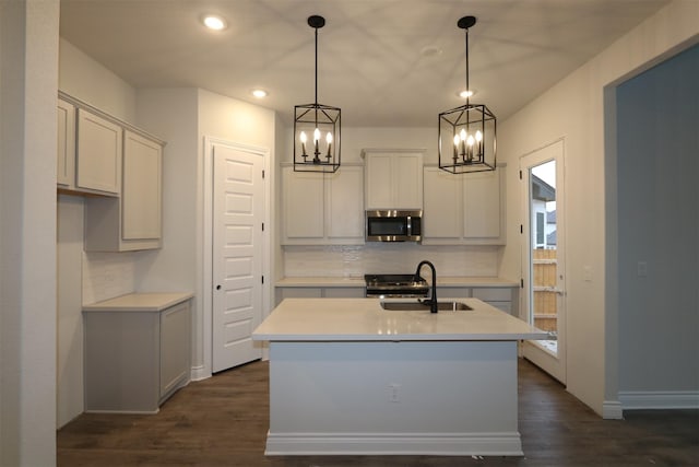 kitchen featuring dark hardwood / wood-style floors, a center island with sink, hanging light fixtures, and sink