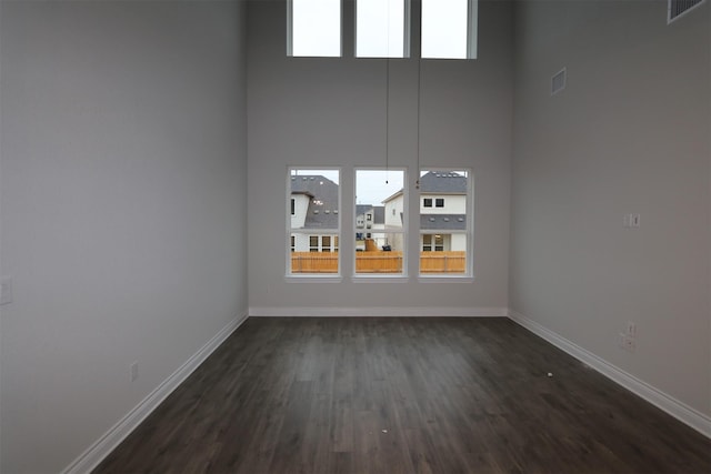 empty room featuring dark wood-type flooring and a high ceiling