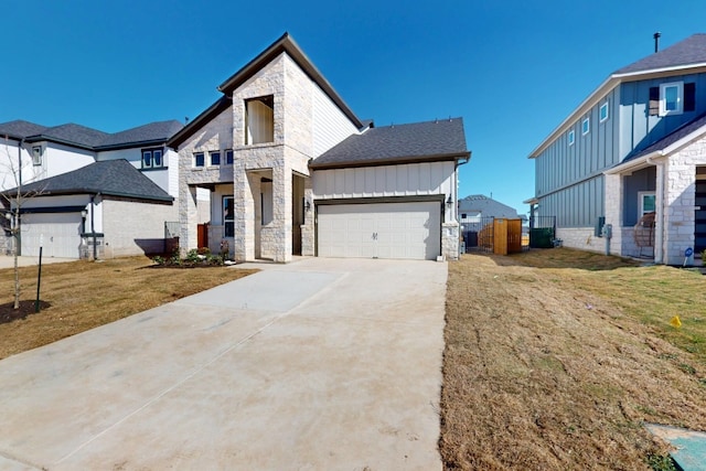 view of front of home featuring stone siding, a front yard, concrete driveway, and an attached garage