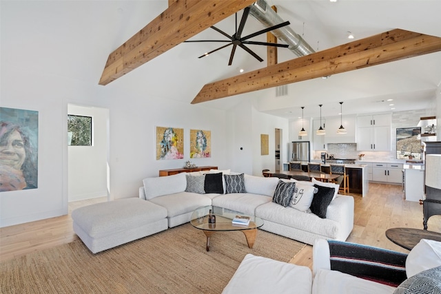 living room featuring high vaulted ceiling, beam ceiling, light hardwood / wood-style floors, and ceiling fan