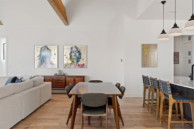 dining space featuring beamed ceiling and light wood-type flooring