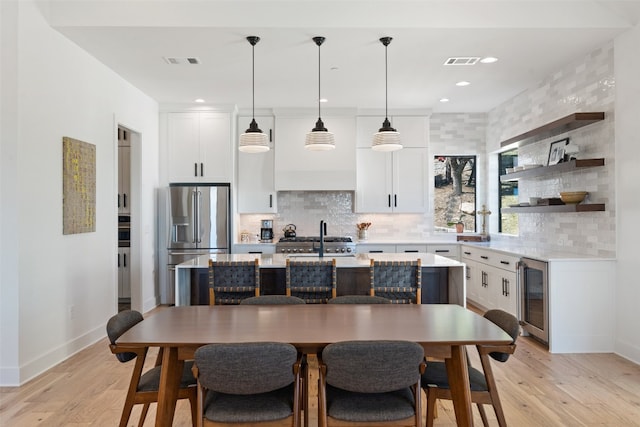 kitchen featuring beverage cooler, white cabinetry, stainless steel refrigerator with ice dispenser, and a center island