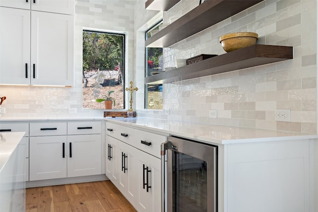 kitchen featuring wine cooler, light hardwood / wood-style flooring, decorative backsplash, and white cabinetry