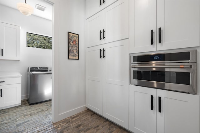 kitchen featuring white cabinets, washer / clothes dryer, stainless steel oven, and dark hardwood / wood-style flooring