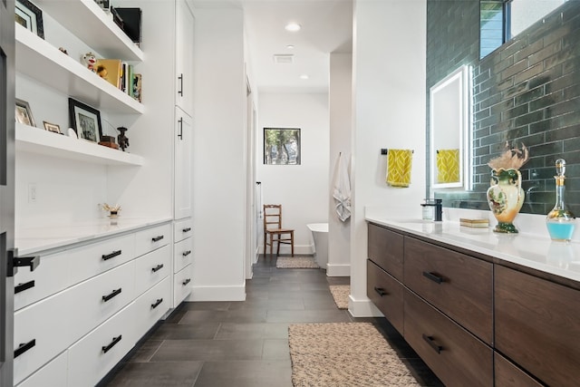 bathroom with a tub to relax in, tile patterned flooring, vanity, and tasteful backsplash