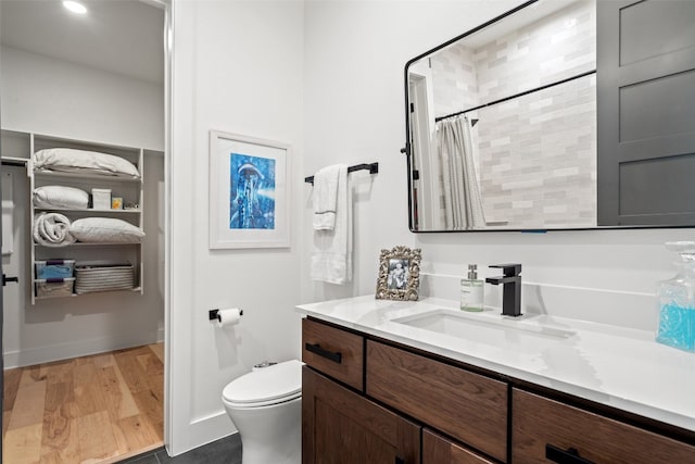 bathroom featuring hardwood / wood-style floors, walk in shower, vanity, and toilet