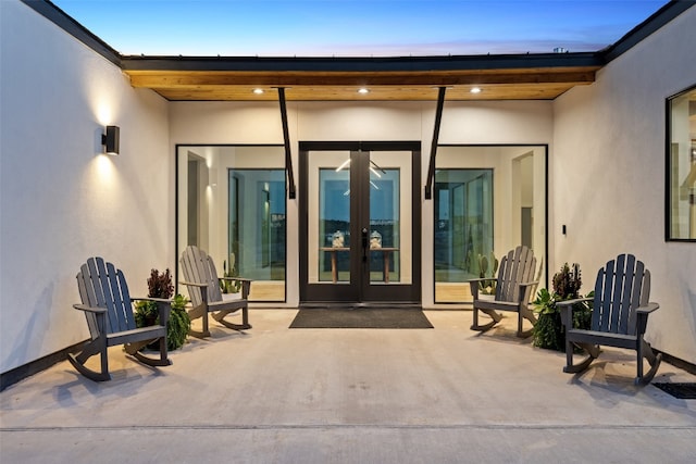 exterior entry at dusk featuring french doors and a patio area