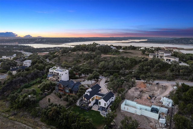 aerial view at dusk featuring a water view