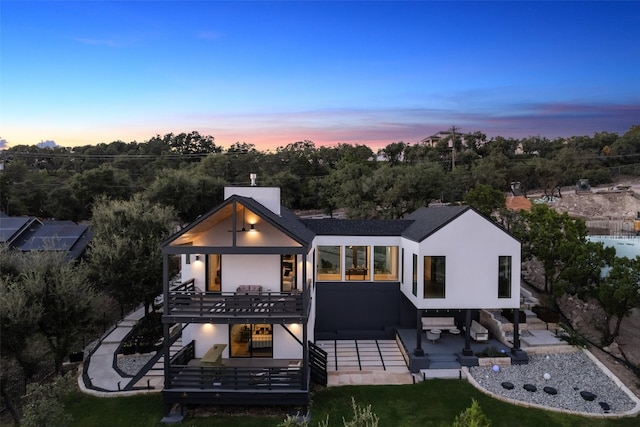 back house at dusk with a patio area