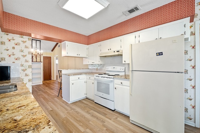 kitchen featuring white appliances, a textured ceiling, decorative light fixtures, white cabinetry, and light wood-type flooring