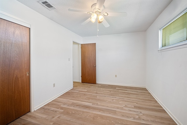 unfurnished bedroom featuring light wood-type flooring, a textured ceiling, ceiling fan, and a closet