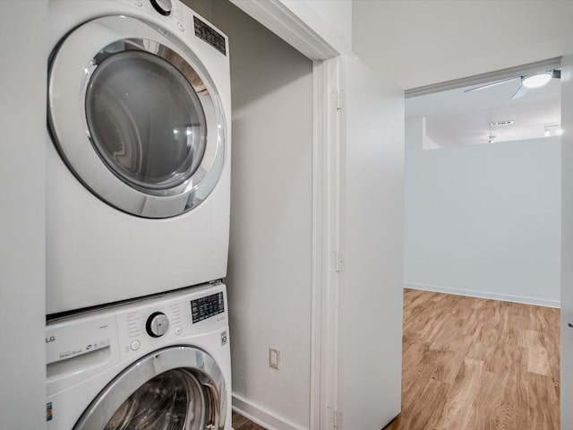 clothes washing area with stacked washer / drying machine and light wood-type flooring