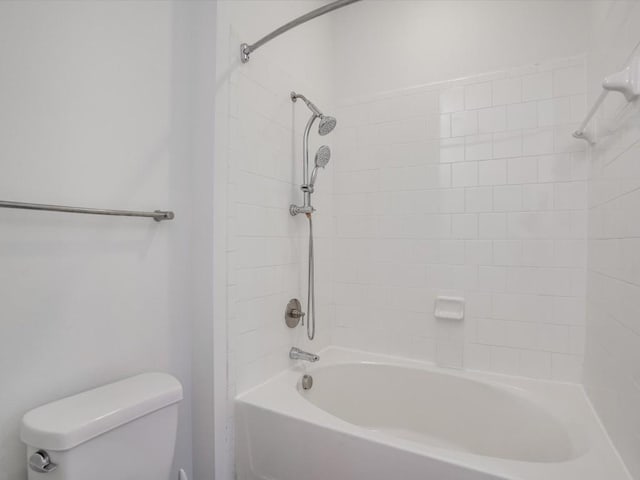 bathroom with tiled shower / bath combo and toilet