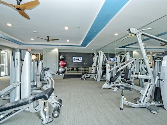 exercise room featuring carpet floors, a tray ceiling, and ceiling fan