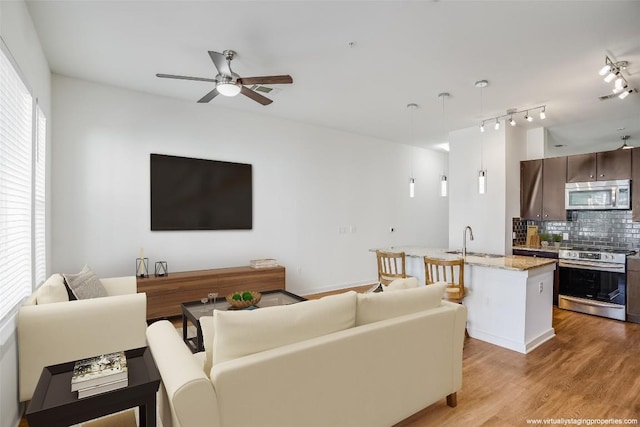 living room featuring light hardwood / wood-style floors, ceiling fan, and sink