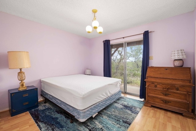 bedroom with a textured ceiling, light wood-type flooring, and access to exterior