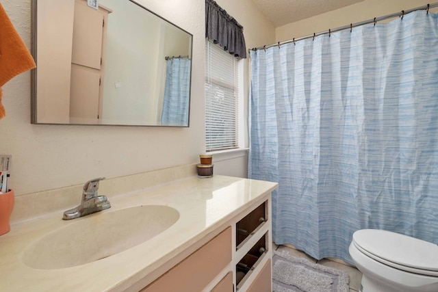 bathroom featuring walk in shower, vanity, toilet, and a textured ceiling