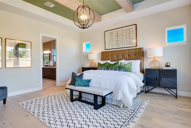 bedroom featuring light hardwood / wood-style floors, connected bathroom, and an inviting chandelier