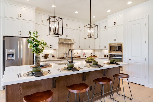 kitchen with a breakfast bar area, pendant lighting, a center island with sink, and stainless steel appliances