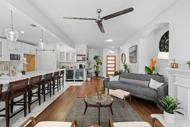 living room with light wood-type flooring, beverage cooler, and ceiling fan