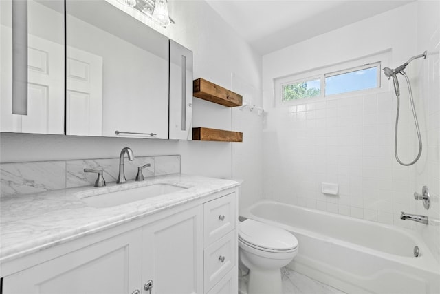 full bathroom featuring vanity, tiled shower / bath combo, and toilet