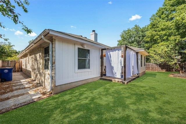 rear view of property featuring a lawn and a storage shed