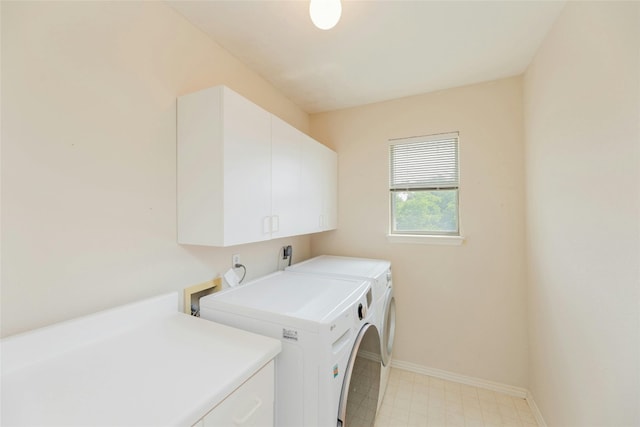 clothes washing area with washer and clothes dryer and cabinets