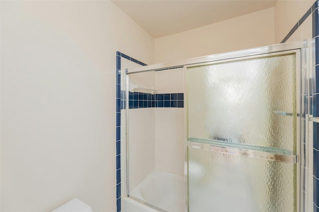 bathroom featuring shower / bath combination with glass door and toilet