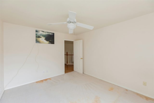 empty room featuring ceiling fan and light colored carpet