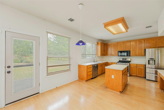 kitchen with appliances with stainless steel finishes, light hardwood / wood-style floors, a center island, and pendant lighting