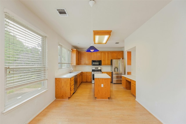 kitchen with light hardwood / wood-style floors, a kitchen island, sink, and stainless steel appliances