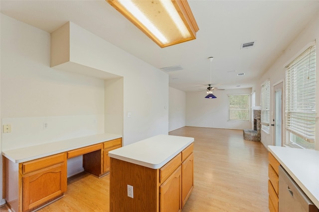 kitchen with ceiling fan, a kitchen island, built in desk, dishwasher, and light hardwood / wood-style floors