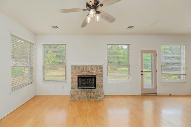 unfurnished living room with a brick fireplace, light hardwood / wood-style floors, and ceiling fan