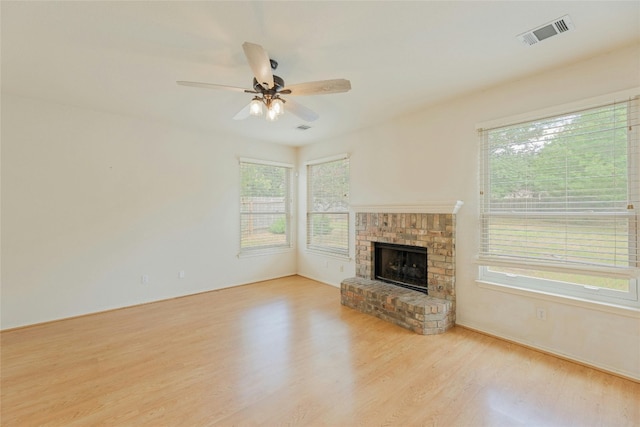 unfurnished living room with a brick fireplace, light hardwood / wood-style floors, and ceiling fan