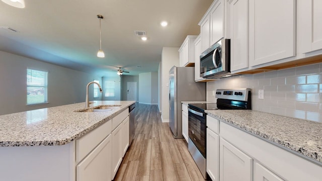 kitchen with sink, white cabinets, light hardwood / wood-style flooring, a center island with sink, and appliances with stainless steel finishes