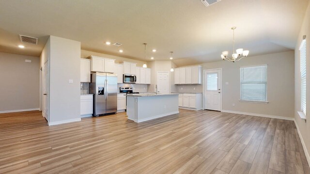 kitchen featuring appliances with stainless steel finishes, hanging light fixtures, light hardwood / wood-style floors, and white cabinetry