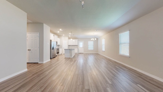 unfurnished living room with sink, light hardwood / wood-style flooring, and a chandelier