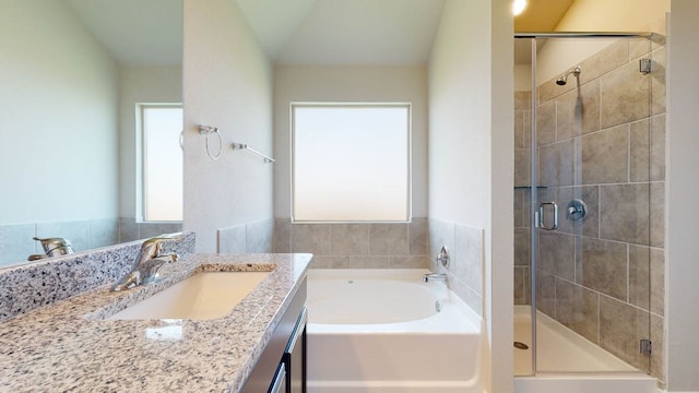 bathroom with vaulted ceiling, independent shower and bath, and vanity