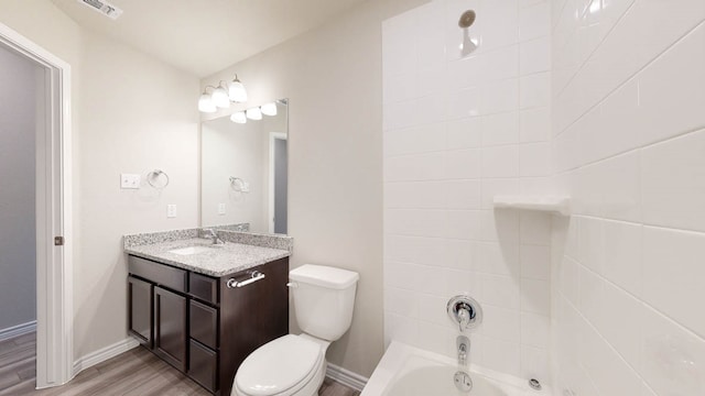 full bathroom featuring tiled shower / bath combo, vanity, hardwood / wood-style floors, and toilet