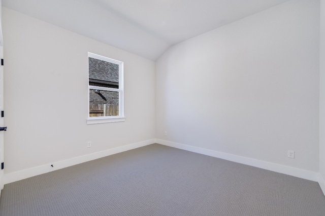 carpeted spare room featuring lofted ceiling