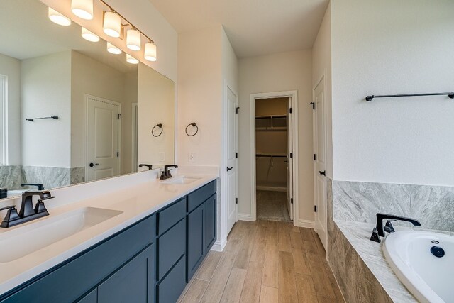 8508 Dongan Dr, Austin, TX 78744 - bathroom with double vanity, a bath, wood finished floors, and a walk in closet
