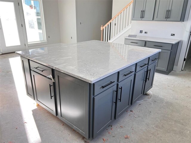 kitchen featuring gray cabinetry, a kitchen island, and light stone counters