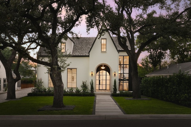 english style home featuring a lawn and stucco siding