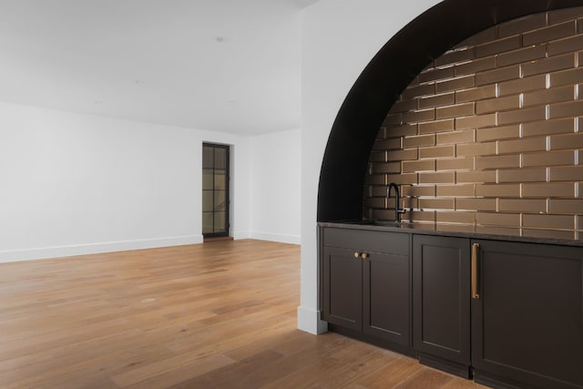 interior space with dark stone counters, light hardwood / wood-style floors, and sink