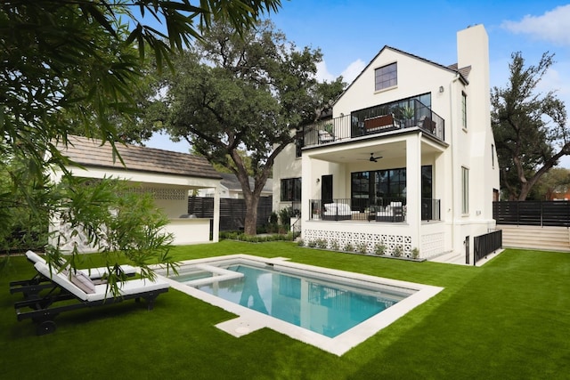 back of house with ceiling fan, a balcony, a lawn, and a patio area