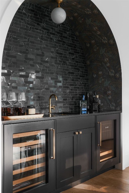 bar featuring sink, wine cooler, hardwood / wood-style flooring, and backsplash